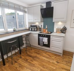 A kitchen with bar stools and modern appliances at The Lookout in Redruth