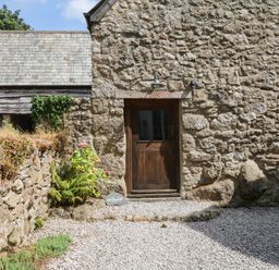 An entrance with a wooden door and stone wall at The Hayloft at Manaton