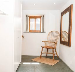 An entryway with a chair and mirror at The Hayloft at Manaton