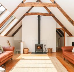 A living room with sofas and a stove at The Hayloft at Manaton