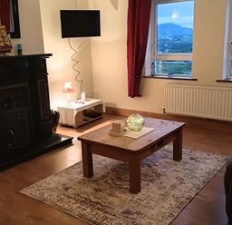 A living room with a fireplace and television at Sliabh League Mountain Lodge TEILEANN near Kilcar, County Donegal