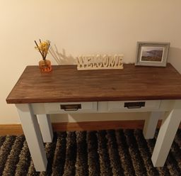 An entryway table with a welcome sign and decorative items at Sliabh League Mountain Lodge in TEILEANN near Kilcar, County Donegal
