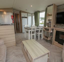 A living room with kitchen area and dining table at 101 Bay View in Ayr