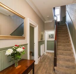A hallway with a staircase and a mirror at Lansdowne Grange in Bridlington
