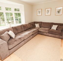 A living room with a sofa and windows at Hedley Dene Cottage in Longhorsley