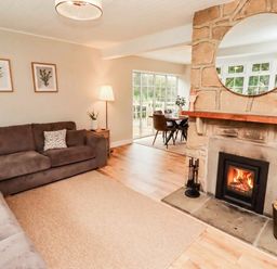 A living room with a sofa and fireplace at Hedley Dene Cottage in Longhorsley