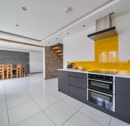 A kitchen and dining area with a staircase and kitchen appliances at The Old Barn in Abergele