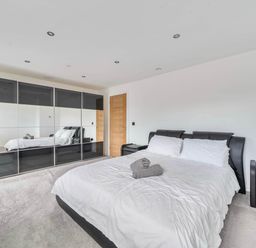 A bedroom with a bed and wardrobe at The Old Barn in Abergele