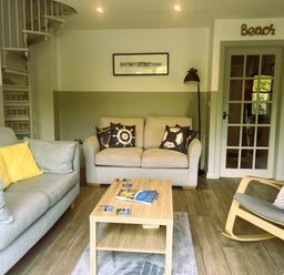 A living room with a sofa, armchair, coffee table, and spiral staircase at 2 Bedrooms overlooking Little Petherick Creek in Little Petherick