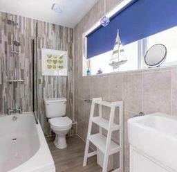 A bathroom featuring a bathtub, toilet, sink, and storage shelf at 2 Bedrooms overlooking Little Petherick Creek in Little Petherick