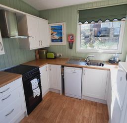 A kitchen with cabinets, oven, sink, and dishwasher at Forest Retreat Sleeps 4 2Bed with Parking Woolsery near Bideford