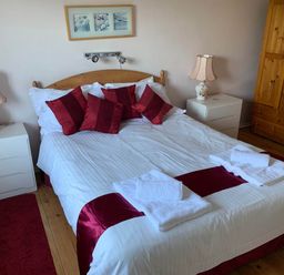 A bedroom with a bed, bedside lamps, and a dresser at House Sleeps 8 Close to Beach Free parking, Mullion