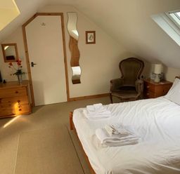 A bedroom with a bed and armchair at House Sleeps 8 Close to Beach Free parking in Mullion