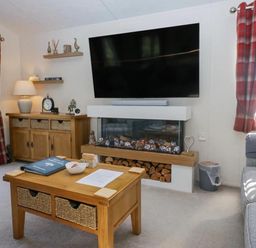 A living room with a sofa, television, and coffee table at Lakeland Lodge 3Bed 2 Bath Private Patio, Carnforth