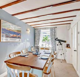 A dining room featuring a table with chairs and a telescope at Cottage Sleeps 5 with Parking and Garden, Carreglefn