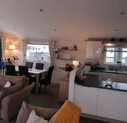 A living room with a dining area and kitchen units at Seaside Lodge Retreat in Eyemouth