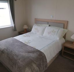 A bedroom with a bed and lamp at Seaside Lodge Retreat in Eyemouth