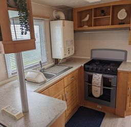 A kitchen with a sink, cooker, and refrigerator at Sandy Paws Dog Friendly Anderby Creek