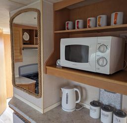 A kitchen with a microwave and mugs at Sandy Paws Dog Friendly Anderby Creek