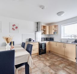 A kitchen with a dining table and appliances at Spacious 3 Bed House Sleeps 6 Parking Wifi in Newquay
