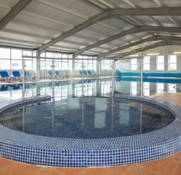 An indoor pool area with a jacuzzi and lounging chairs at 2Br Lodge Pool Fireplace PetsOK Parking Goonhavern