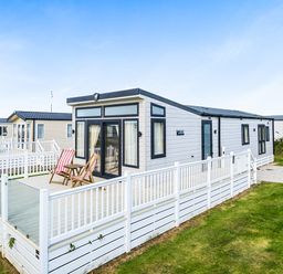 A caravan with a deck and chairs at 2Br Lodge Pool Fireplace PetsOK Parking Goonhavern
