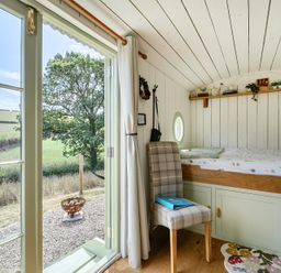 A bedroom with a bed and chair at Cosy Luxury Owls Roost Hut with Private Hot Tub near Little Deptford Farm near Umberleigh