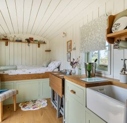 A bedroom with a bed and a kitchen area at Cosy Luxury Owls Roost Hut with Private Hot Tub, Little Deptford Farm near Umberleigh
