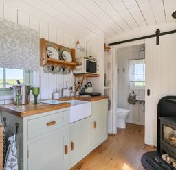 A kitchen with a sink and wood stove at Cosy Luxury Owls Roost Hut with Private Hot Tub Little Deptford Farm near Umberleigh