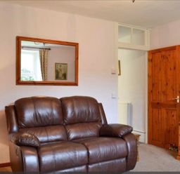 A living room with a sofa and a television stand at The Old Barn in Manchester