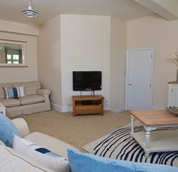 A living room with a sofa and television at 4 The Salcombe in Salcombe