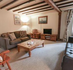A living room with sofas, a coffee table, and a television at Dewi Villa Apartment in Aberaeron