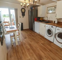 A kitchen with appliances and a dining table at The Hideaway at Monterey in Helston