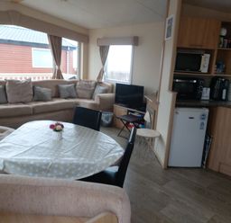 A living room with sofa and kitchen area at Golden Sands FSB38 Rhyl