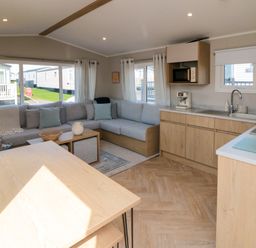 A living room with a sofa and kitchen area at 5 Rowen Court Scarborough