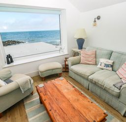 A living room with a large window overlooking the sea at Y Glyn in Borth