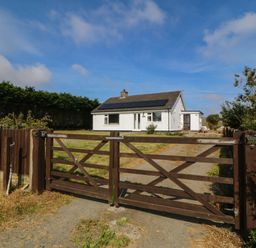 A house with a gate and grassy area at Wilpol Llanerchymedd
