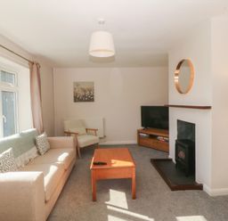 A living room with a sofa, coffee table, and television at Wilpol in Llanerchymedd