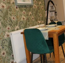 A dining table with chairs and decorative wallpaper at Blackburn Heights Apartment 1 in Bridlington
