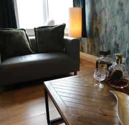 A living room with a sofa, table, and decorative items at Cornerhouse Apartment 1 Llandudno