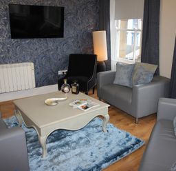A living room with a television, sofas, and a coffee table at Cornerhouse Apartment 2 Llandudno