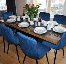 A dining room with a set table and blue chairs at Cornerhouse Apartment 2 in Llandudno