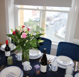 A dining room table set with plates and wine bottles at Cornerhouse Apartment 2 in Llandudno