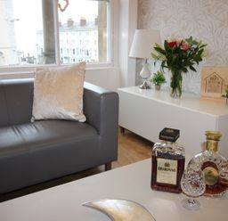 A living room with a sofa, coffee table, flowers, and decorative items at Cornerhouse Apartment 3 in Llandudno