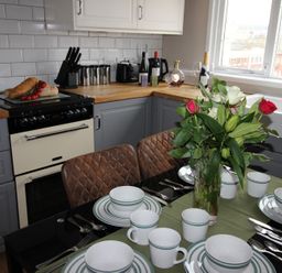 A kitchen with a dining table set and an oven at Cornerhouse Apartment 4 Llandudno