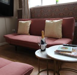 A living room with a sofa, coffee table, and television at Cornerhouse Apartment 5 in Llandudno