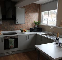 A kitchen with oven, sink, and table at Cornerhouse Apartment 5 in Llandudno
