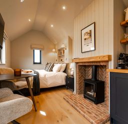 A studio with a bed, fireplace, and kitchen unit at 2 West Dunkirk Neuk in Humshaugh