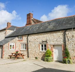A stone building with windows and a door at The Cheese House near Charmouth