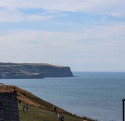 A view of the sea and cliffs with people walking at 26 Metropole Towers in Whitby